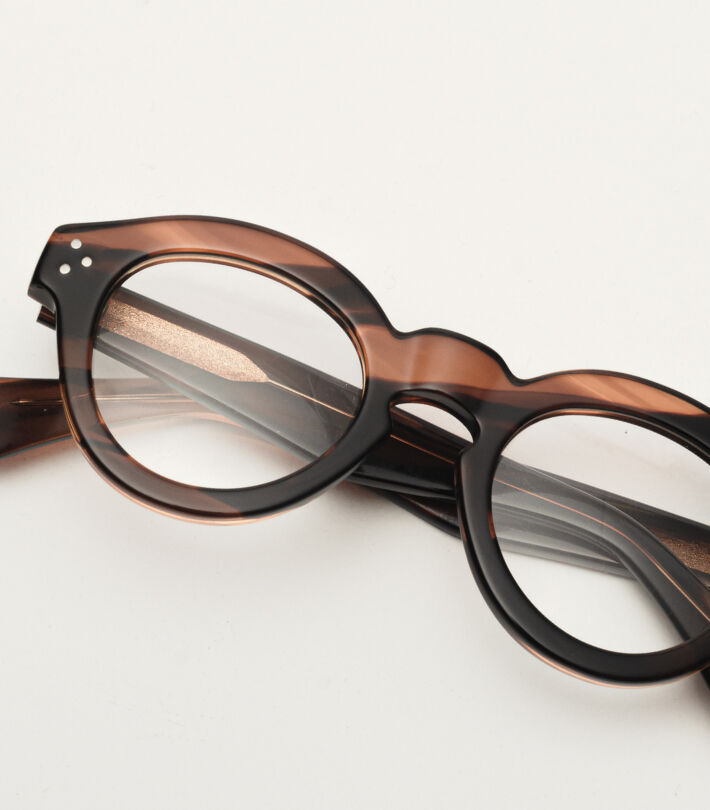 Rounded tortoiseshell glasses with a glossy finish resting on a white surface.