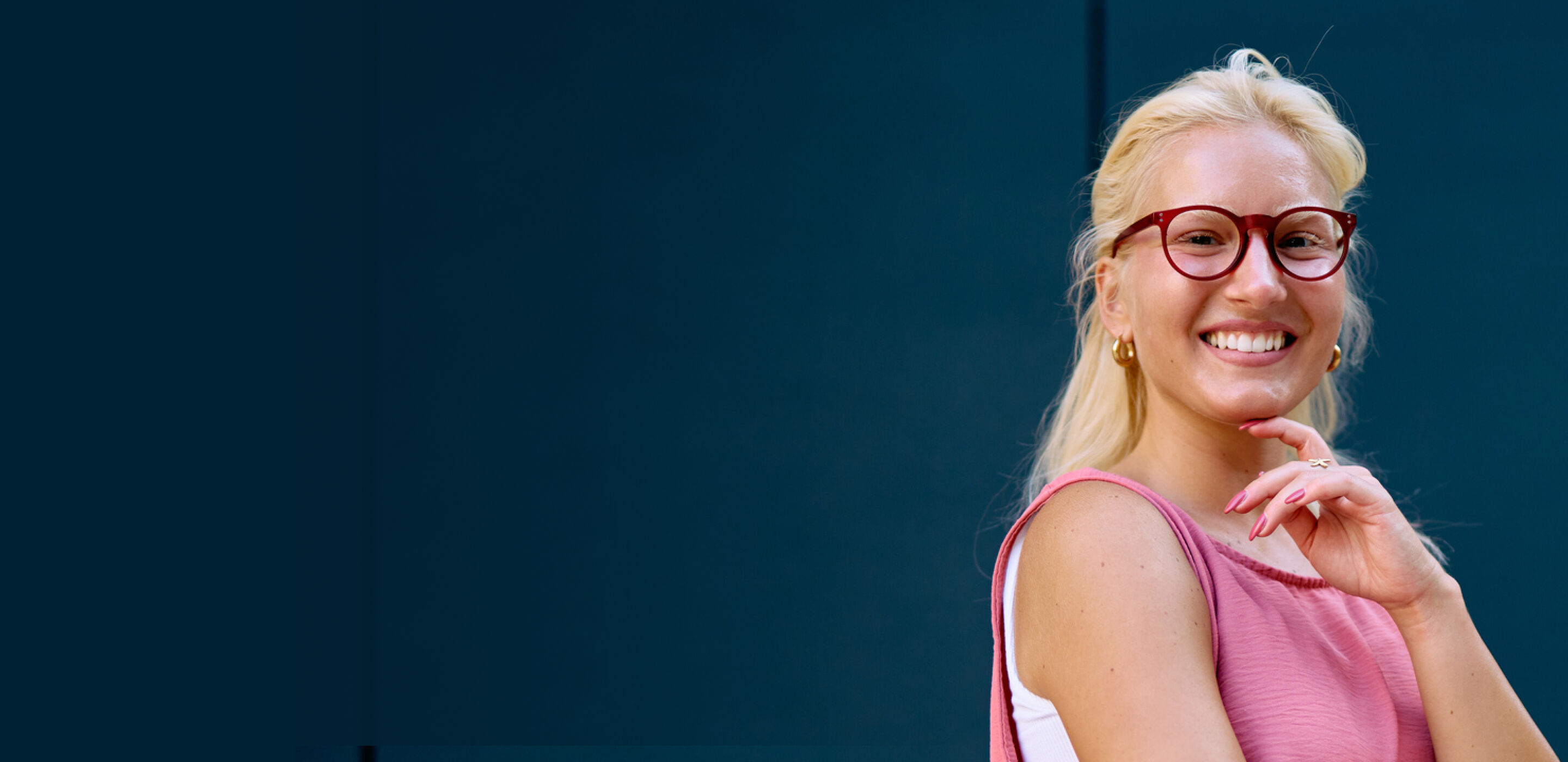 Smiling woman wearing red sunglasses, showcasing stylish Nordic inspired look