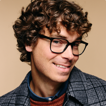 Smiling man with curly hair wearing glasses