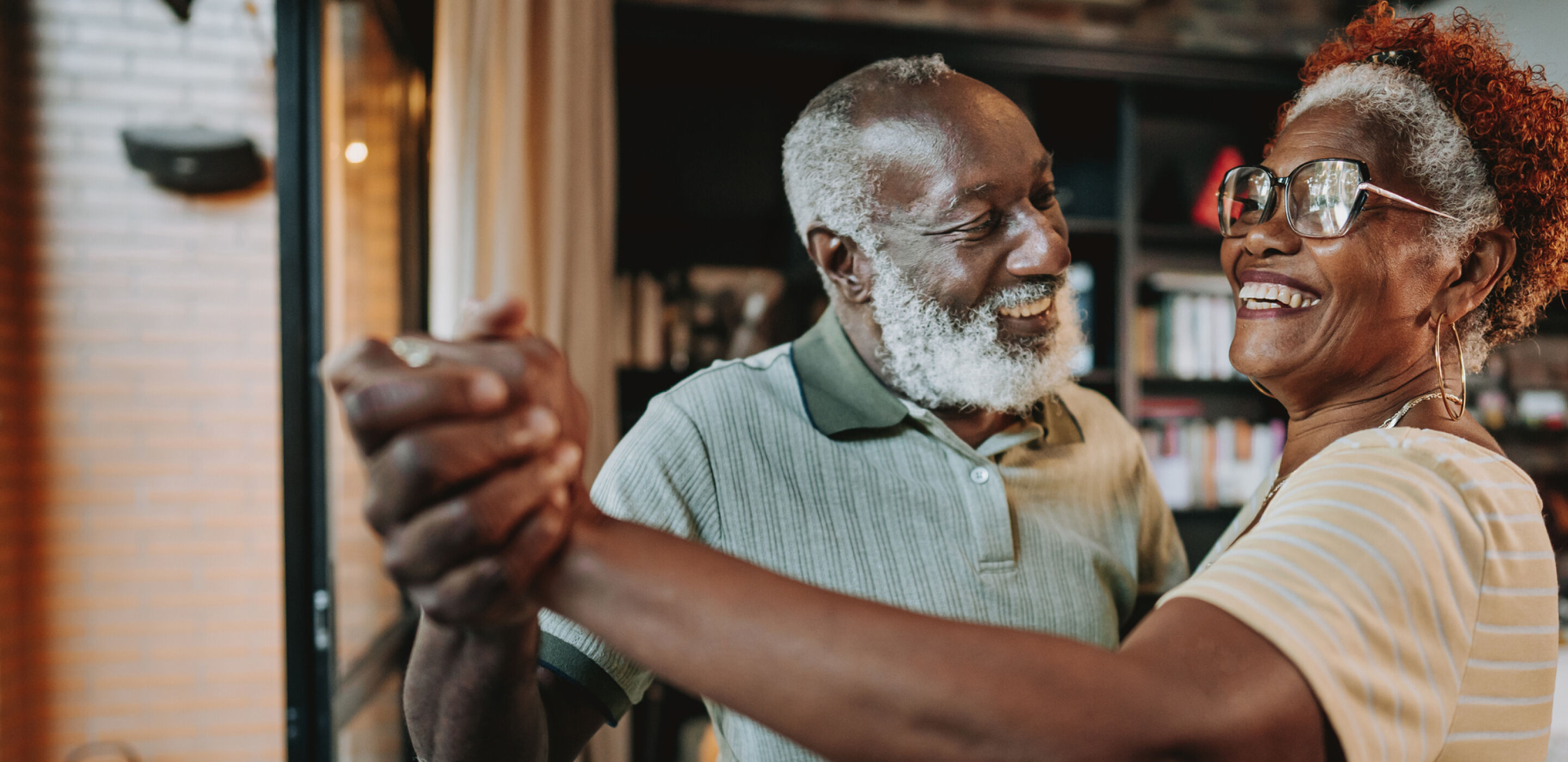 Elderly couple smiling while embracing at home, highlighting comfort, confidence, and clear vision.