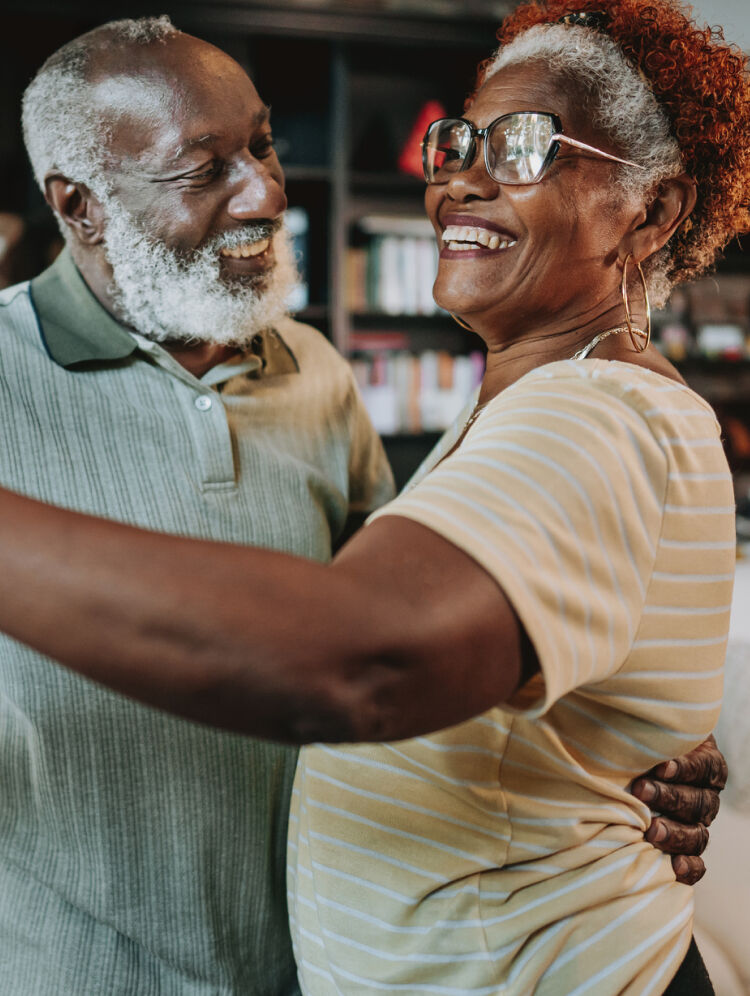 Elderly couple smiling while embracing at home, highlighting comfort, confidence, and clear vision.