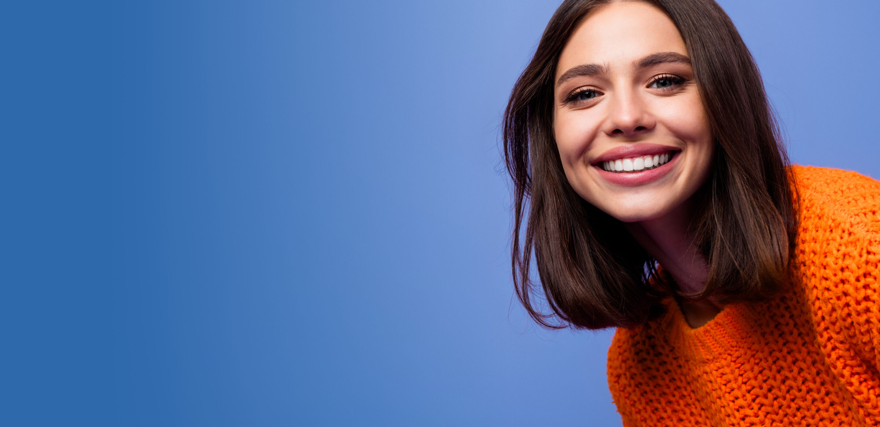 Smiling woman with short brown hair wearing an orange sweater, representing friendly contact lens advice.