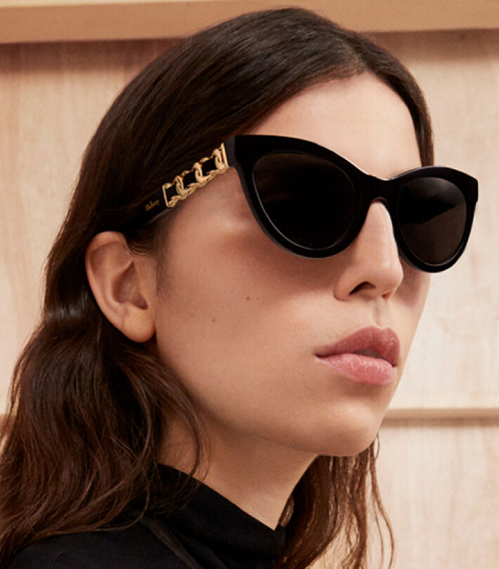 Model wearing Mulberry black cat-eye sunglasses with gold chain detailing from the Mulberry eyewear collection