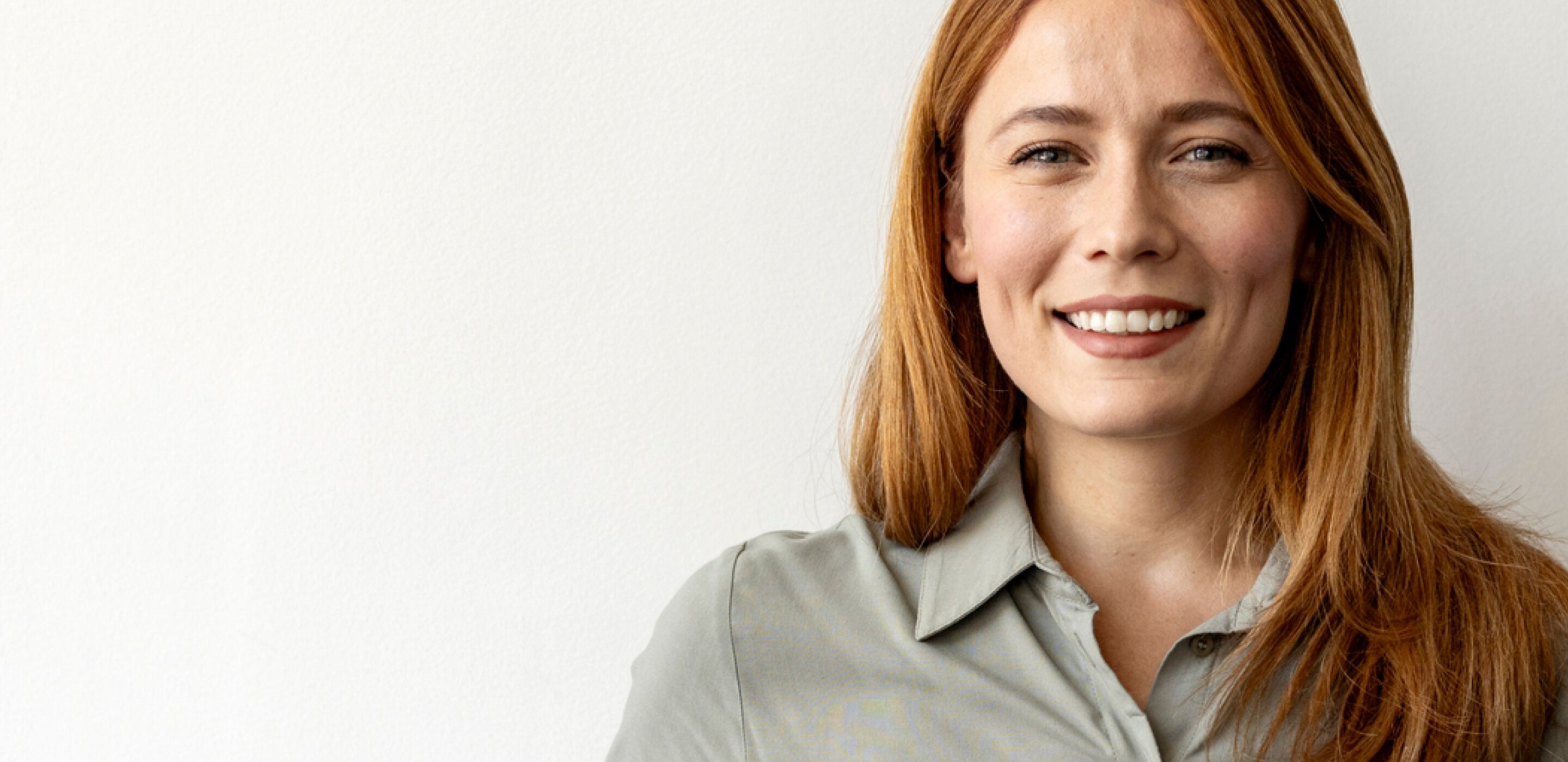 Smiling woman with long red hair wearing a green shirt happy with Combined eye test at boots opticians