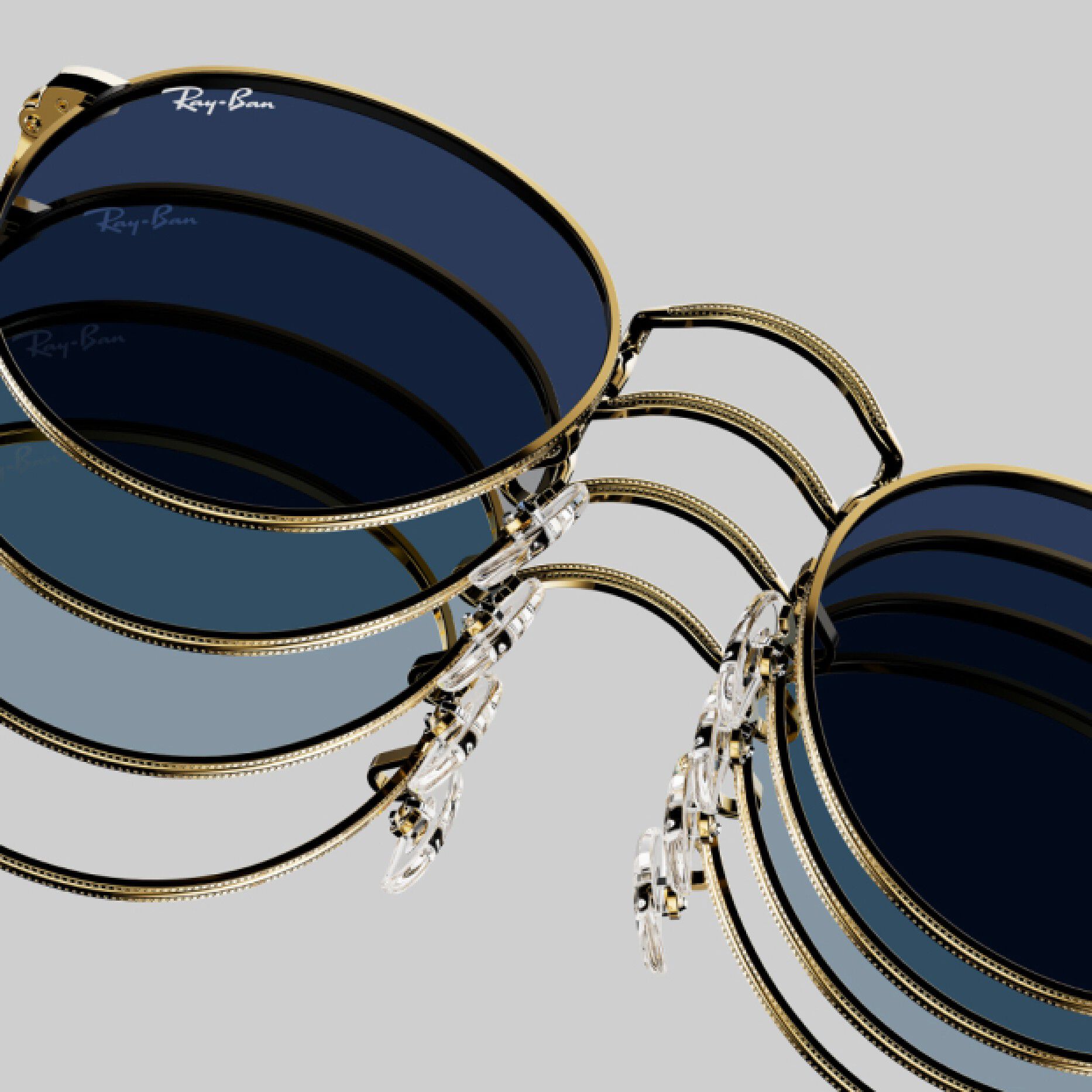 Round black Ray-Ban sunglasses with gold frames arranged on light gray background