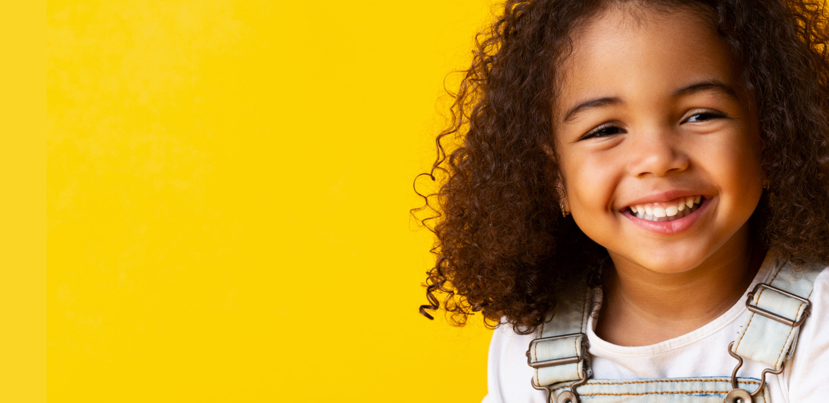 Smiling child with curly hair showing healthy, happy vision