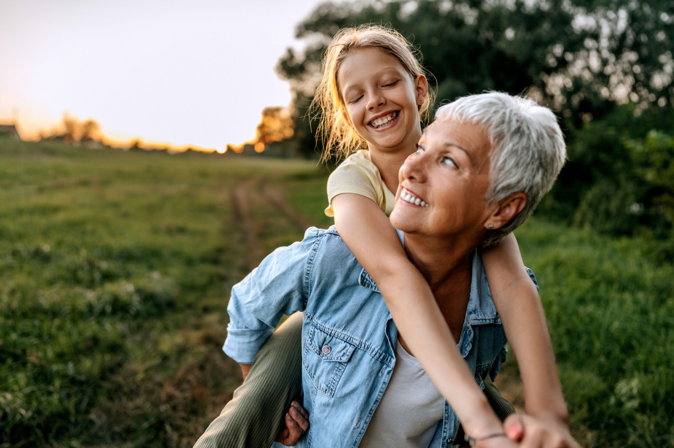 Older woman carrying a child outdoors, reflecting eye health monitoring for overall wellbeing