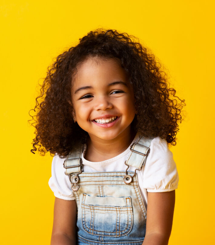 Smiling child with curly hair showing healthy, happy vision