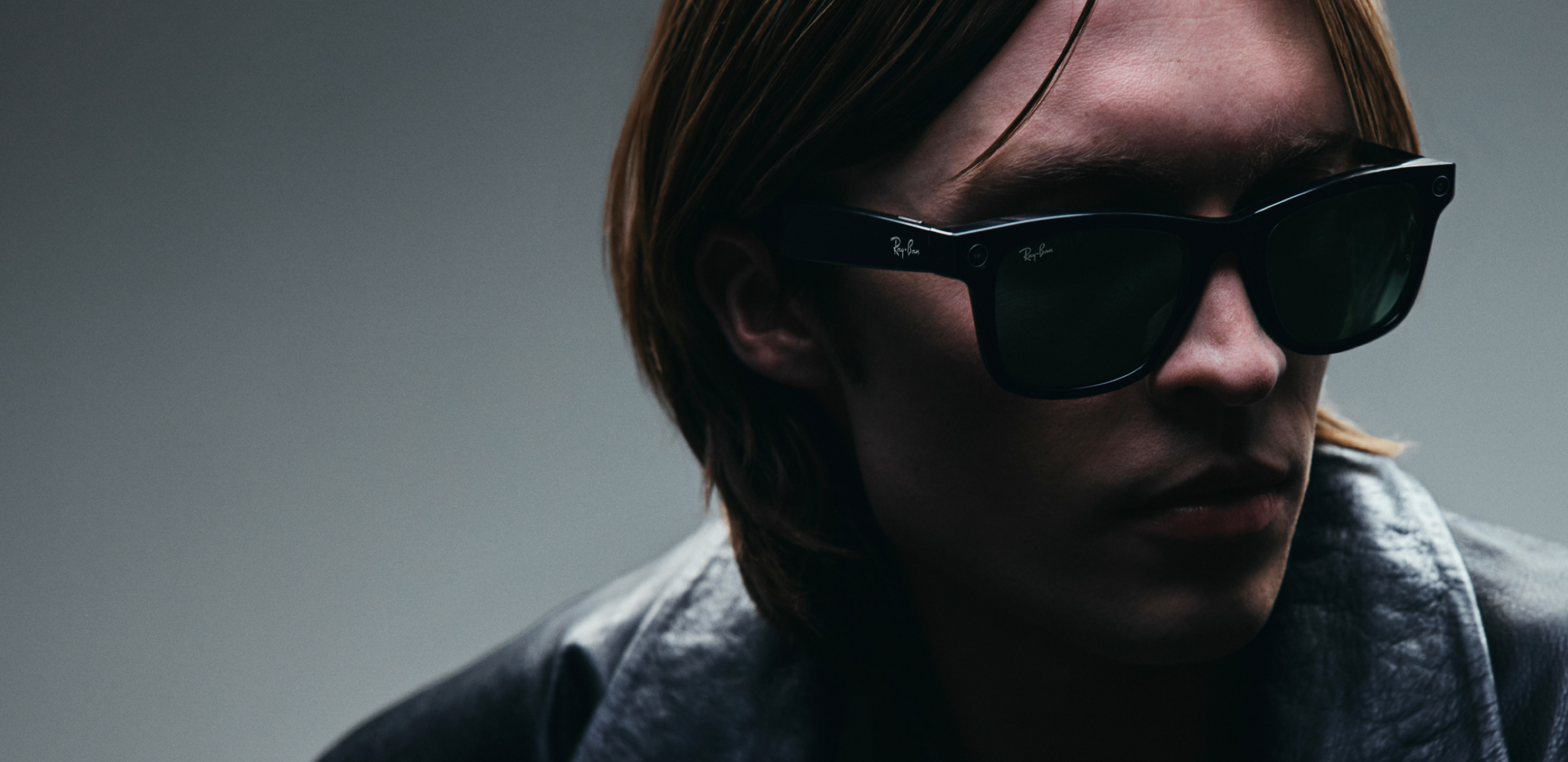 Person with long hair wearing dark AI Glasses with Transitions&reg; Lenses, moody vibe