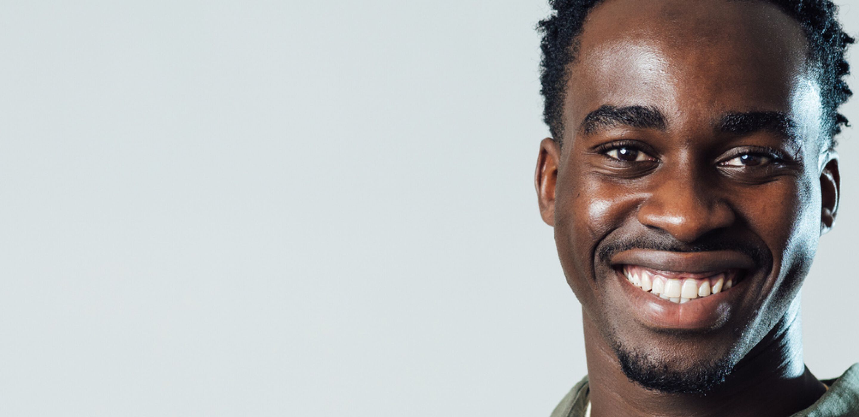 Smiling man with short curly hair against a plain light background.