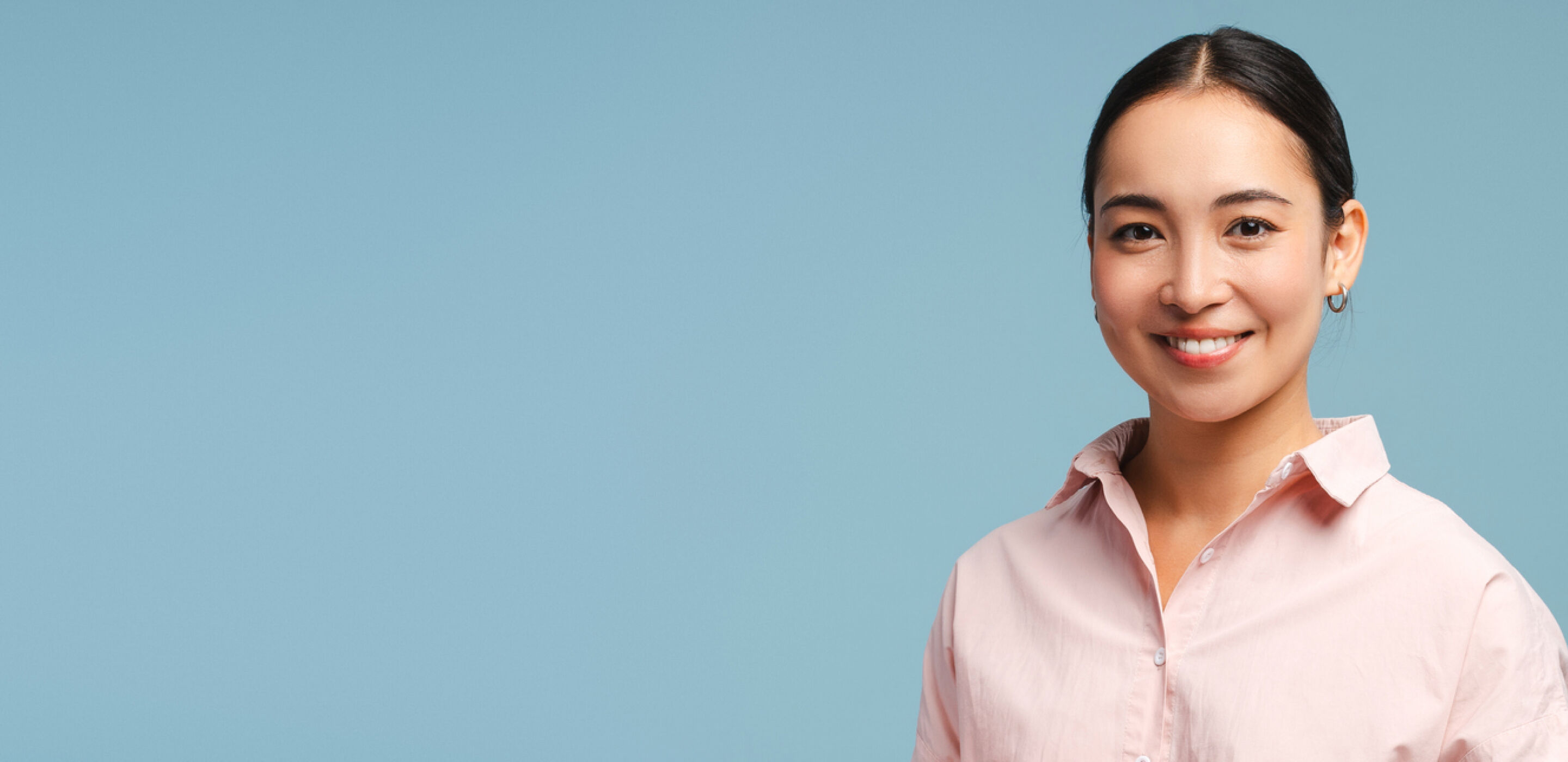 Smiling woman in pink top against blue background, confident contact lens wearer