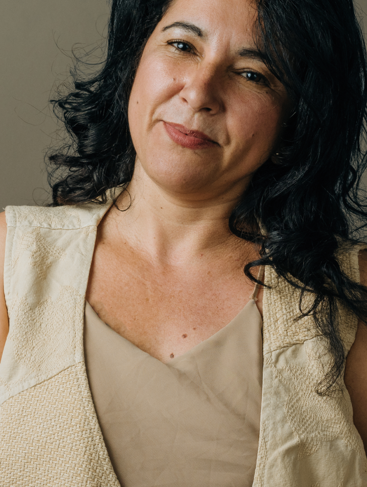 Woman with dark curly hair smiling warmly, representing comfort during a dry eye evaluation.