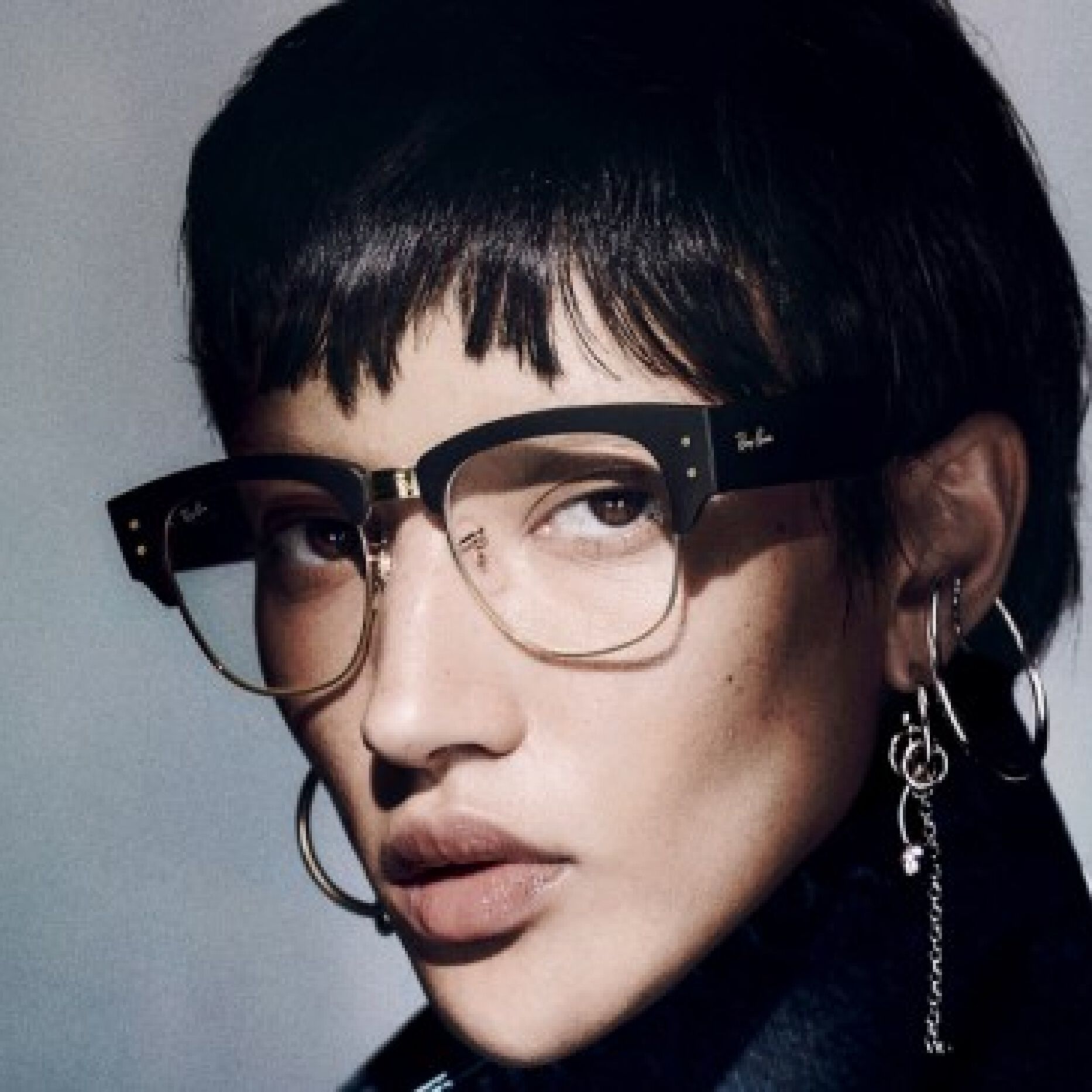 Person with short hair wearing bold Ray-Ban eyeglasses, confident modern style