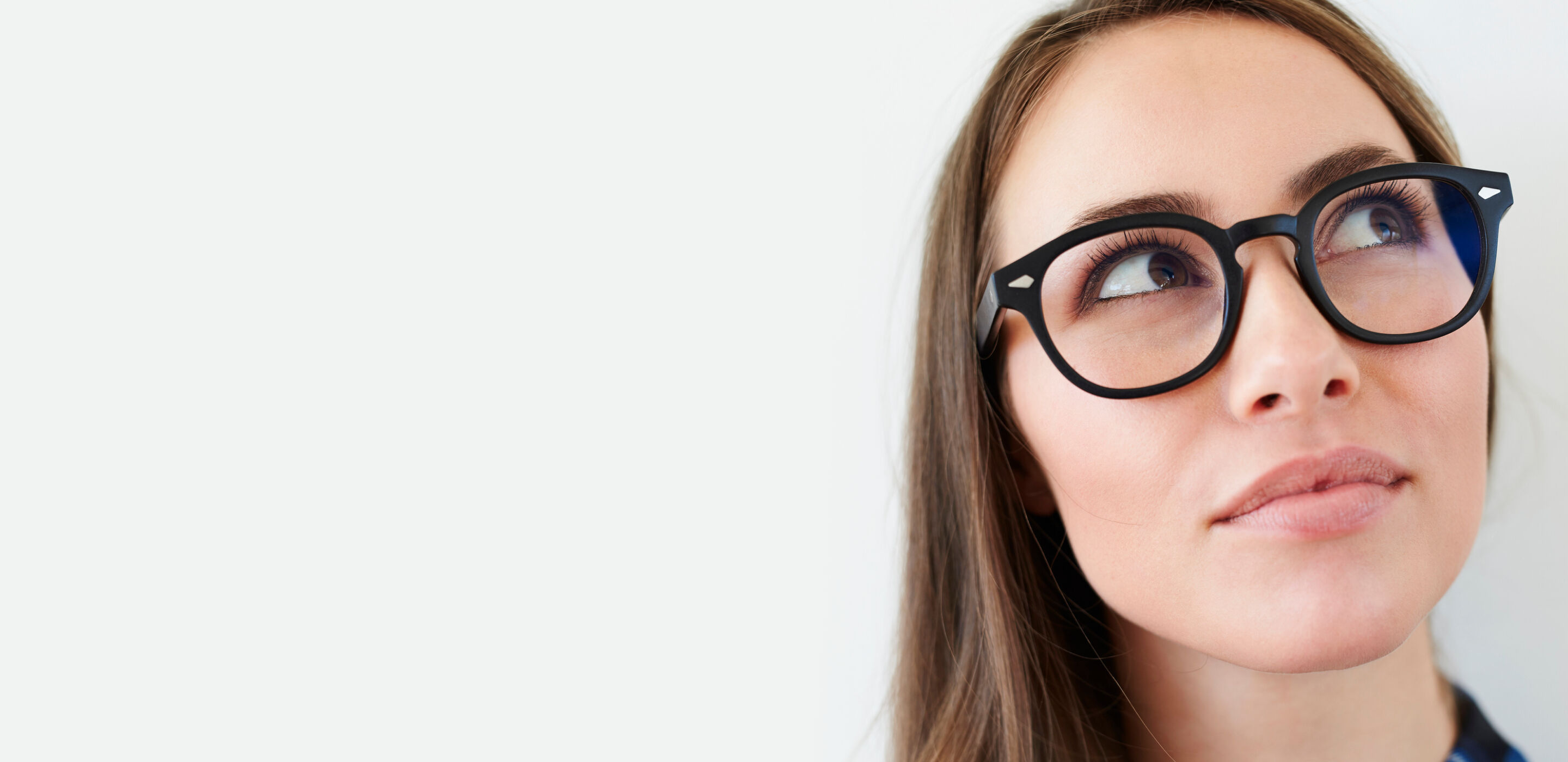 Young woman with black boots opticians glasses looking upward thoughtfully.